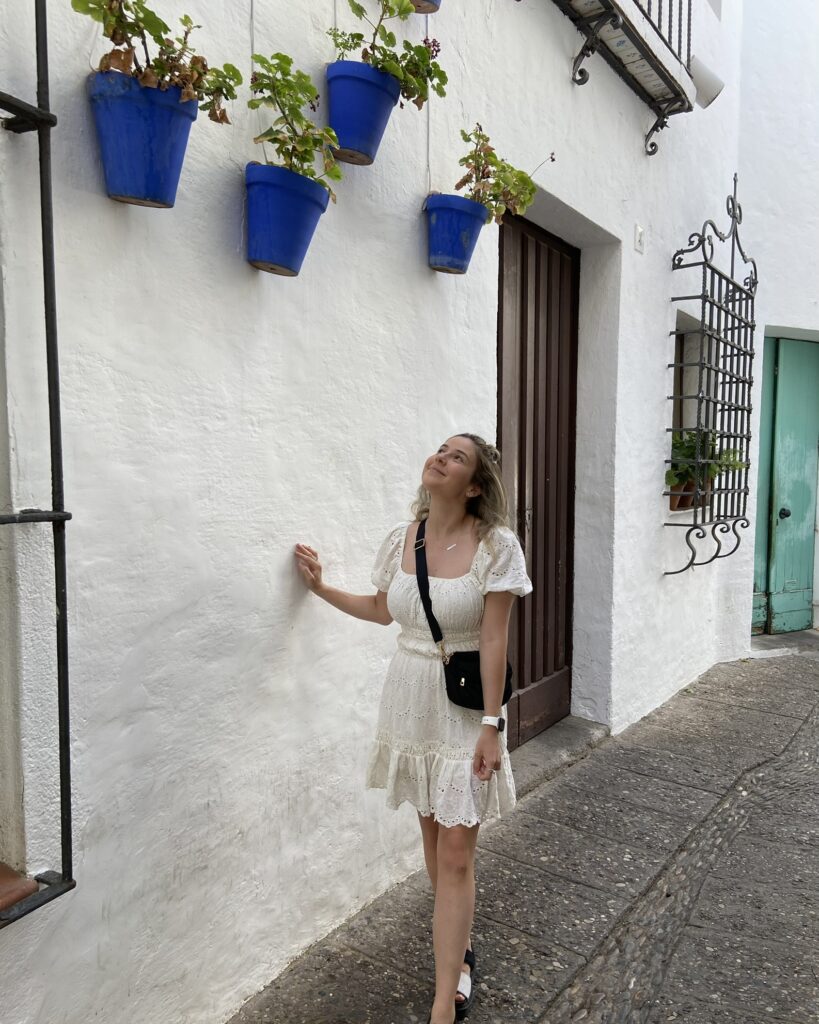 Woman in white dress looking up at blue plant pots